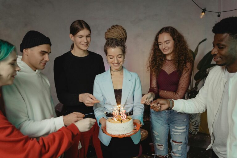 Diverse group of young adults celebrating a 21st birthday party with cake and sparklers indoors