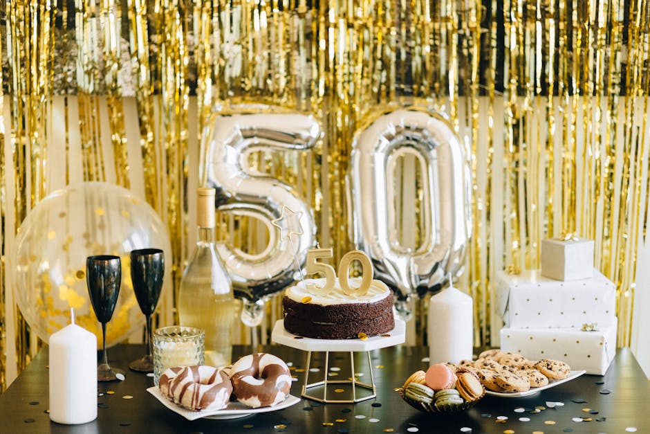 Gold-themed 50th birthday party table setup with cake, gifts and balloons
