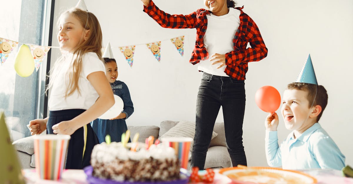 Children having fun at a birthday party with balloons, cake and party hats — age-appropriate kids birthday party ideas