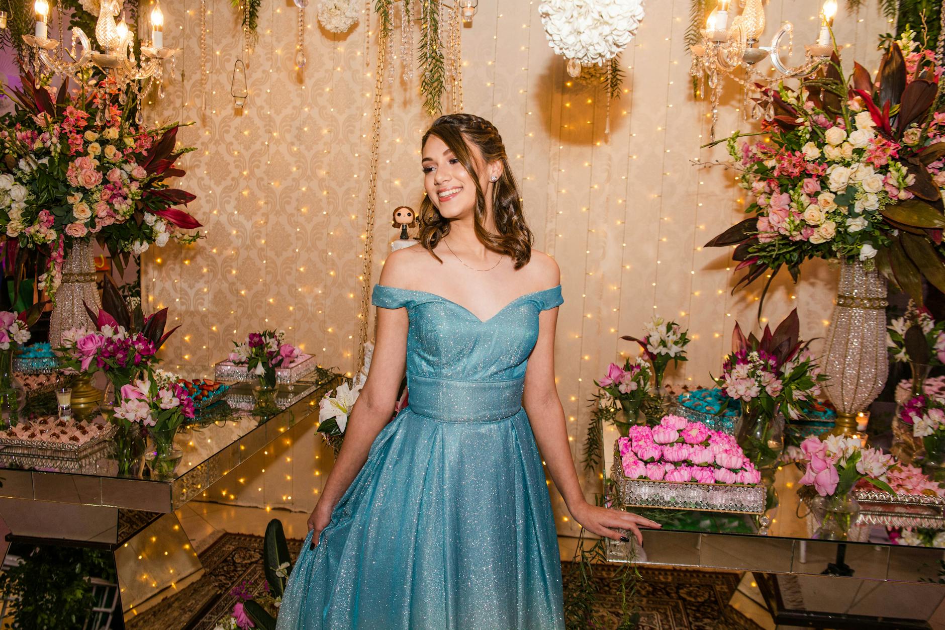 Teenage girl in a glamorous gown celebrating her Sweet 16 birthday party surrounded by floral decorations