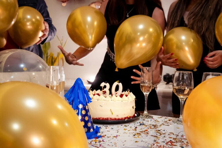 Adults celebrating a 30th birthday indoors with balloons and cake