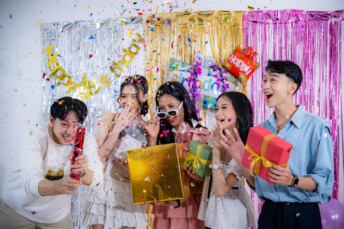 Group of friends celebrating a 40th birthday with gifts and confetti, showing how shared experience gifts bring people together