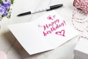 Open birthday greeting card beside a pen, ready to write a heartfelt message
