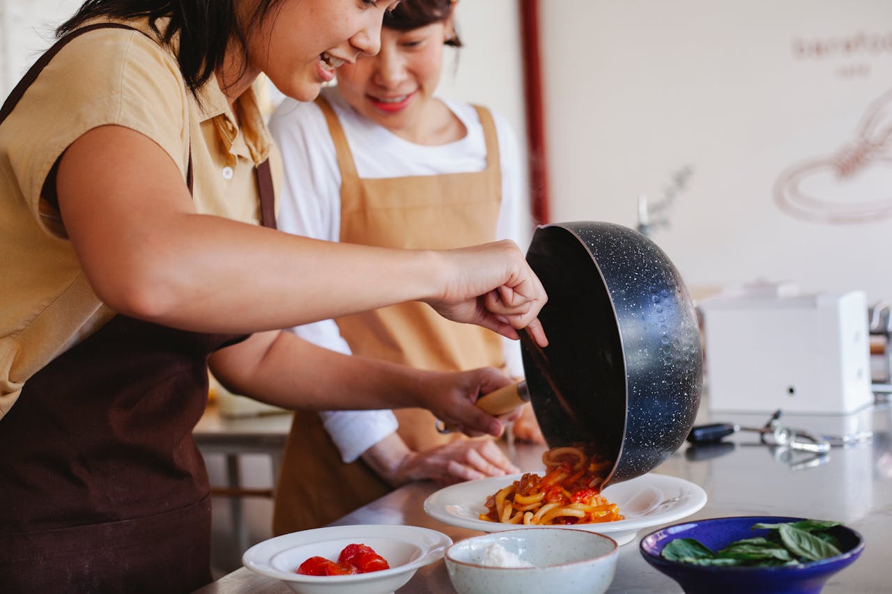 Two women in aprons at a cooking class, making fresh pasta together as a birthday experience gift