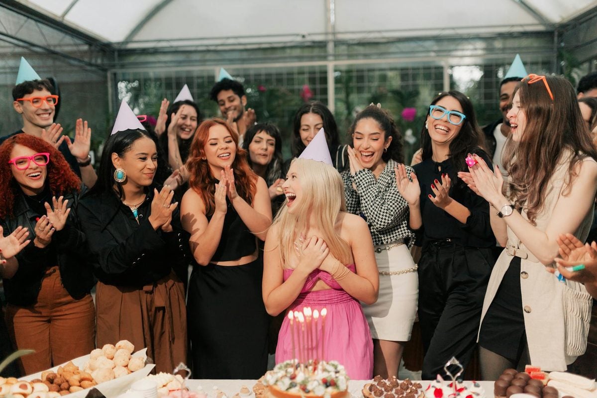 Group of friends joyfully celebrating a birthday party indoors with food, drinks and laughter