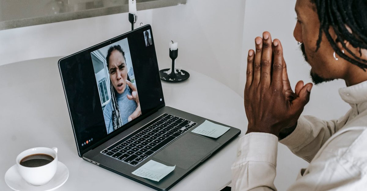 Person on a video call with their partner on a laptop, smiling and waving, representing long-distance birthday love and connection