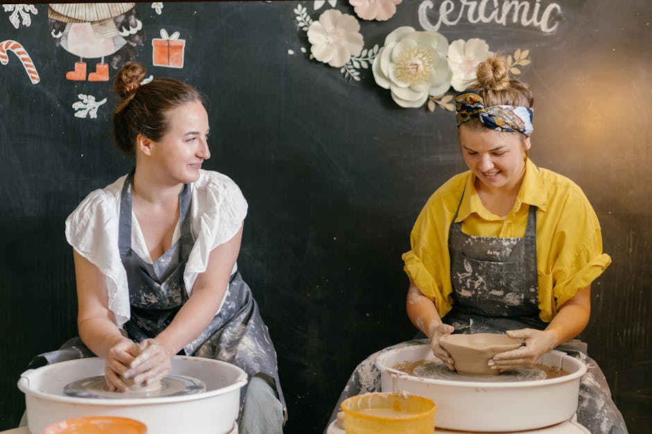 Two women smiling at pottery wheels during a creative ceramics class — a thoughtful birthday experience gift for mum