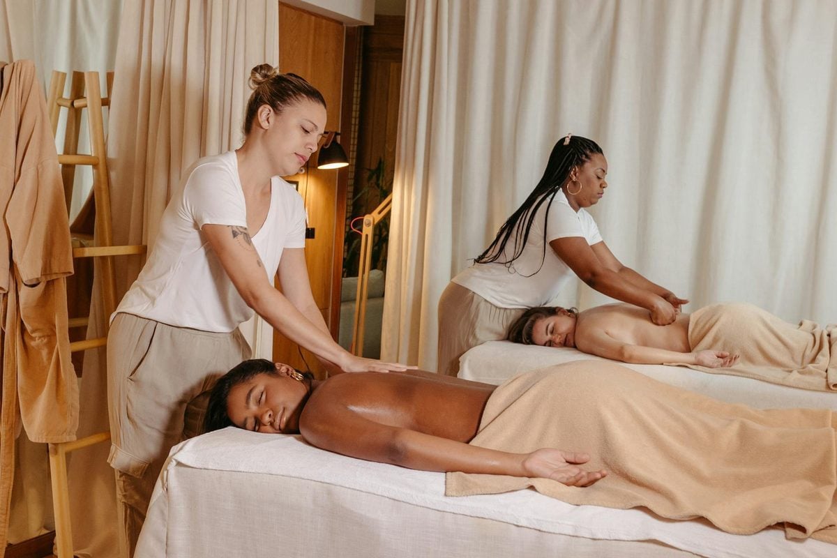 Two women receiving relaxing massages side by side at a serene spa, ideal for a home spa day birthday party for adults