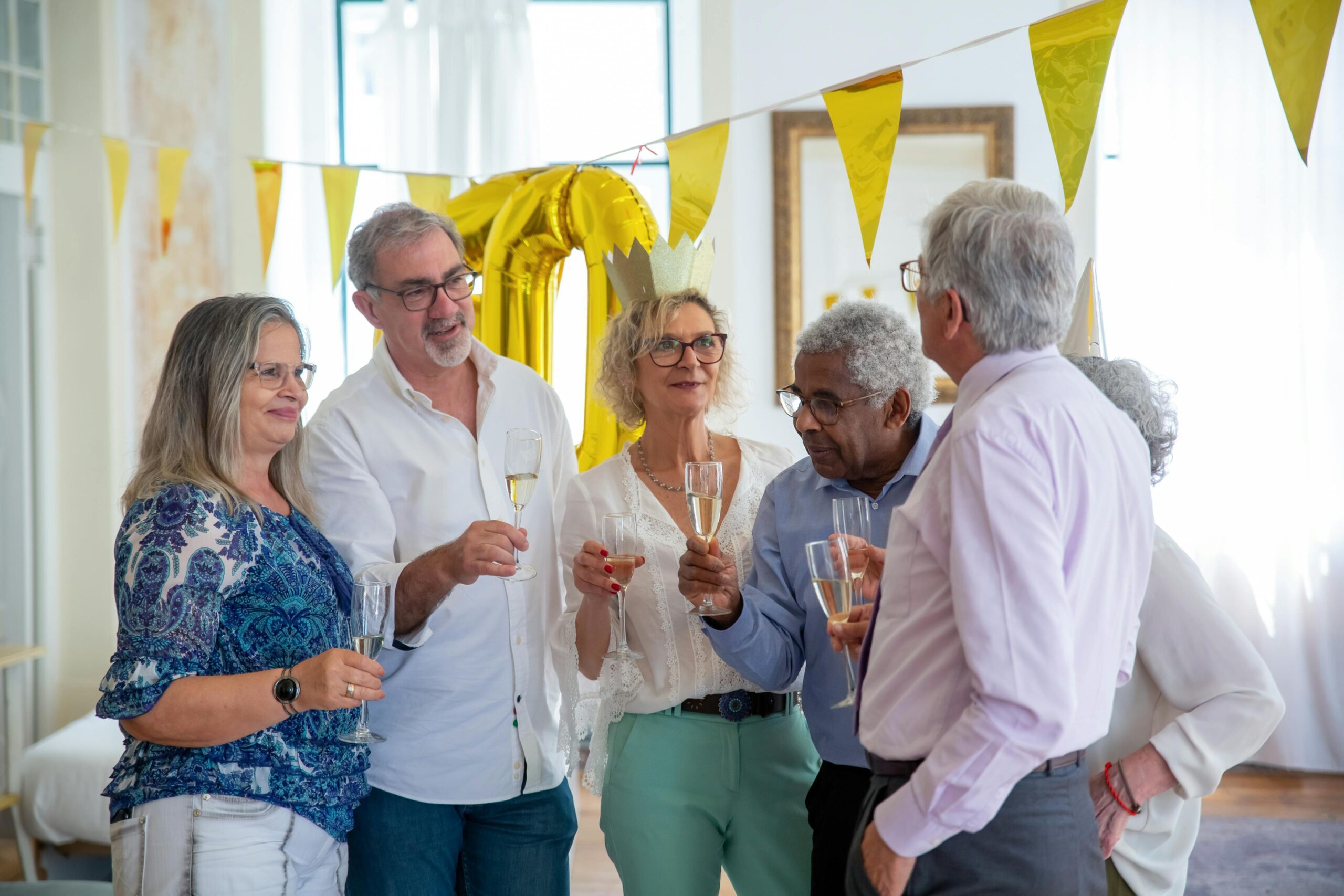 Group of senior adults celebrating a birthday together with champagne glasses and festive decorations